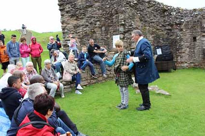 Auf der Wiese vor Urquhart Castle wird das traditionelle Anziehen von Kilts demonstriert Auf der Wiese vor Urquhart Castle wird das traditionelle Anziehen von Kilts demonstriert
