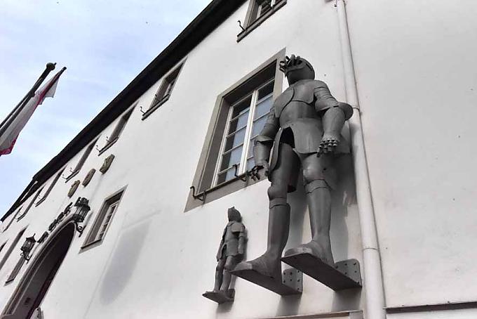 Burg Linz, an deren Fassade Ritterrüstungen prangen. Marienaltar: Maria und Christus nach der Auferstehung.