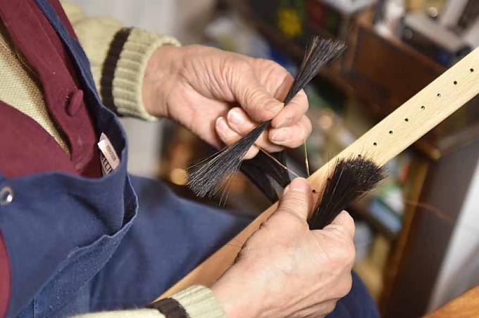 Ursula Römer in ihrem Geschäft und Werkstatt. Interessierte schauen in die Auslage des Bürstengeschäftes von Ursula Römer.