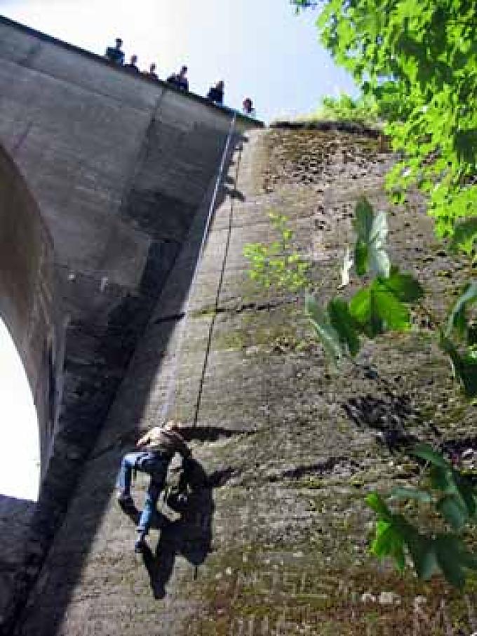 Den Gurt straff zwischen die Schenkel gezurrt, das Seil fest in beiden Händen, seilt sich der erste Mutige aus der Gruppe am Mauerwerk der Brücke senkrecht in die Tiefe ab Den Gurt straff zwischen die Schenkel gezurrt, das Seil fest in beiden Händen, seilt sich der erste Mutige aus der Gruppe am Mauerwerk der Brücke senkrecht in die Tiefe ab