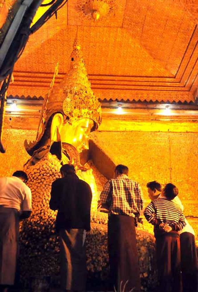 Gläubige tragen Blattgold auf die Figur des goldenen Buddhas auf Gläubige tragen Blattgold auf die Figur des goldenen Buddhas auf