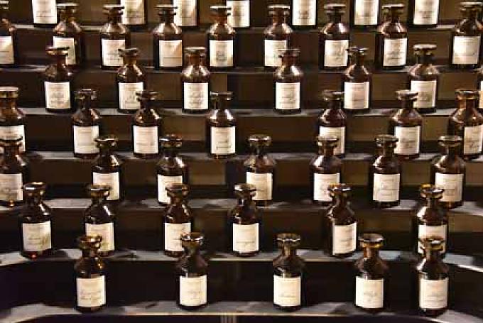 Parfümorgel Besucherin betrachtet einen historischen Destillierapparat