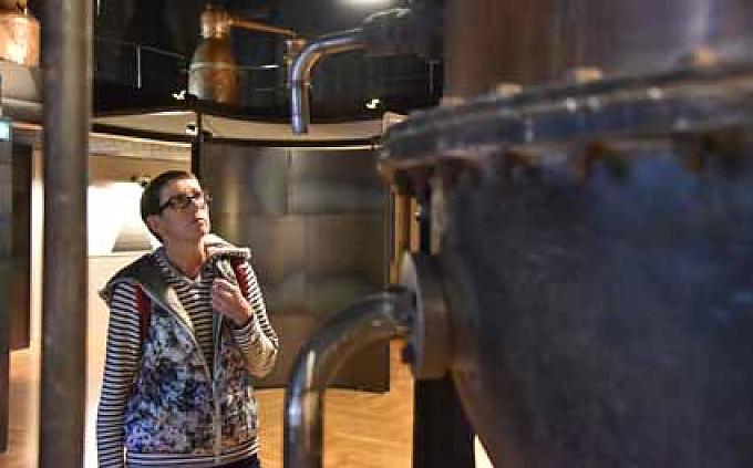 Besucherin betrachtet einen historischen Destillierapparat Besucherin betrachtet einen historischen Destillierapparat