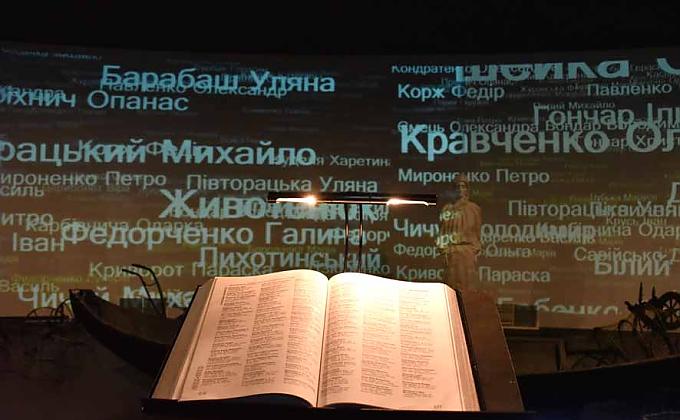 Gedenkbücher, in denen Namen und zum Teil Lebensumstände von Verstorbenen verzeichnet sind. Auf einem dieser Mühlsteine, in die Getreideähren eingraviert sind, liegt ein kleiner rosa Plüschhase.