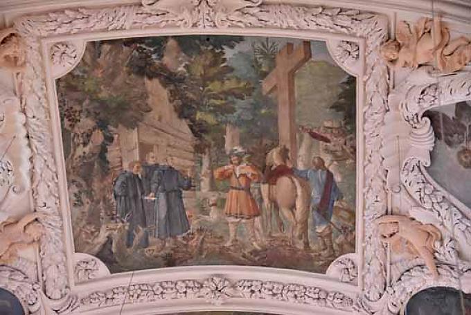 Die Fresken erzählen die Geschichte von der Entstehung der Klosterkirche. In der zweiten trifft Marktgraf Diepold den Einsiedler Gerwig vor seiner Einsiedelei im Wald. Der Einsiedler steht mit zwei Mitbrüdern vor einem einfachen Holzhaus im Wald. Die Fresken erzählen die Geschichte von der Entstehung der Klosterkirche. In der zweiten trifft Marktgraf Diepold den Einsiedler Gerwig vor seiner Einsiedelei im Wald. Der Einsiedler steht mit zwei Mitbrüdern vor einem einfachen Holzhaus im Wald.