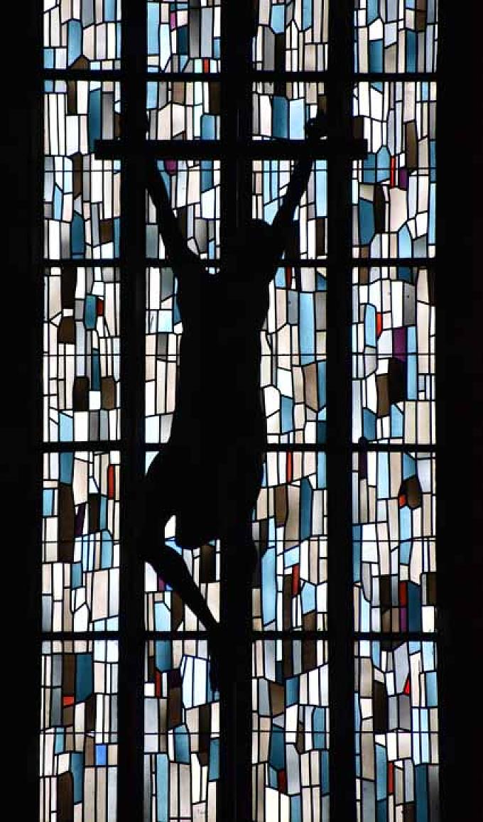 Kruzifix vor einem Glasfenster Kreuzgang