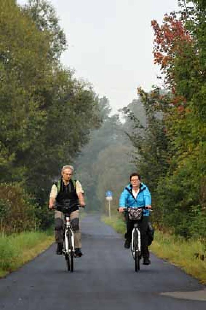 Fahrradfahrer unterwegs auf dem Bahnradweg. Kottreng – in Tracht der Schwälmer Frauen, von Helwig Klippert.
