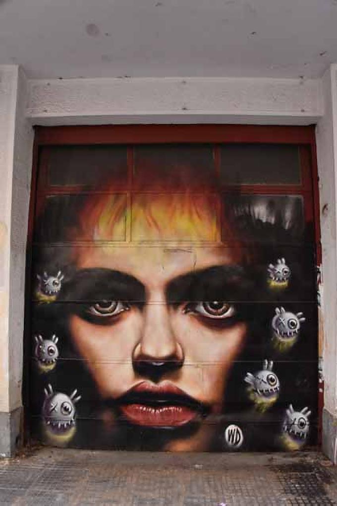 Frauengesicht auf einem Garagentor von dem balinesischen Künstler WD (Wild Drawing). Das Kunstwerk des Athener Künstler STMTS.