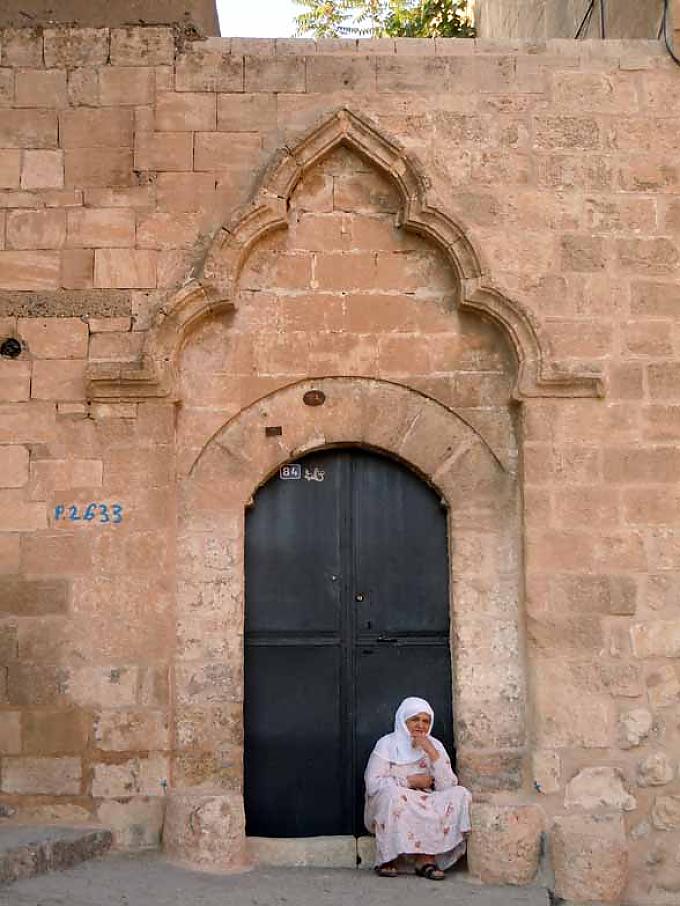 Eine Frau sitzt auf den Stufen vor der Haustür in Mardin. Feier zur Beschneidung. Kleine Jungen werden in Istanbul zu osmanischen Prinzen ausstaffiert.
