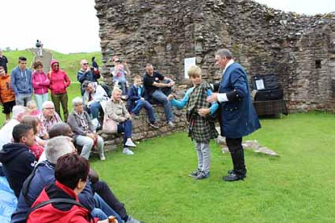 Auf der Wiese vor Urquhart Castle wird das traditionelle Anziehen von Kilts demonstriert