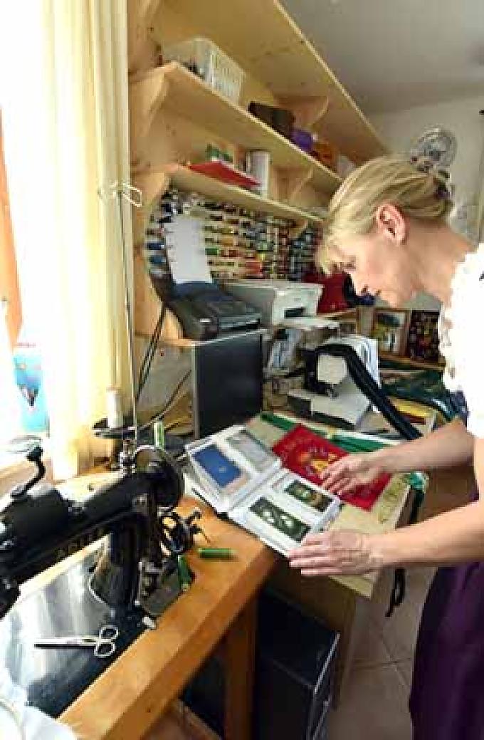Irmi Axmann blättert in ihren Musterbüchern Irmi Axmann in ihrer kleinen Werkstatt.