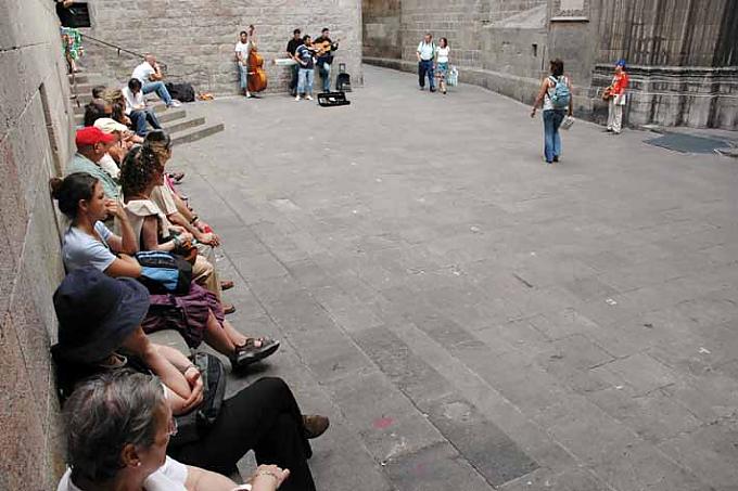 Menschen lauschen Straßenmusikanten im Gotischen Viertel von Barcelona.