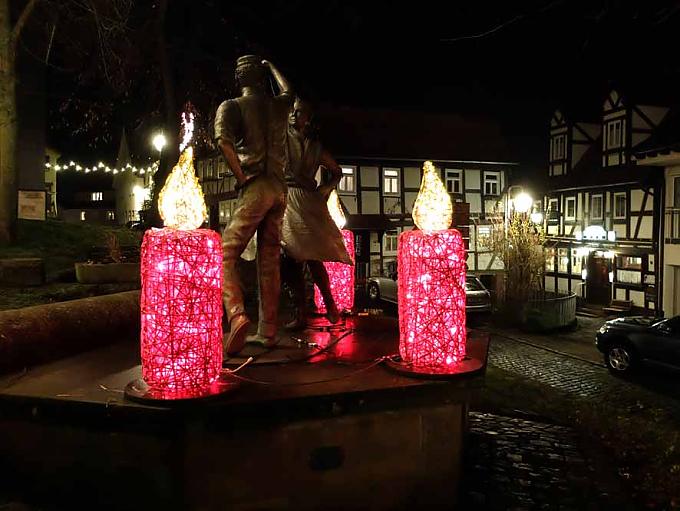 Neben dem Denkmal mit dem tanzenden Paar leuchten den Weihnachtsmarktbesuchern kleine rote Kerzen den Weg.  Die größte Adventskerze der Welt in Schlitz.