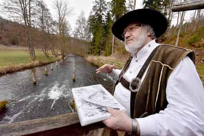 Martin Spreng erklärt Besuchern die Funktion der Wasserstube. Mit dicken Lederhandschuhen bewaffnet, verkeilt Spreng vor den Augen seiner Besucher ein Ende des dünnen Stamms und windet ihn um einen Stab. Die Rinde blättert ab, die Fasern des Holzes teilen sich.