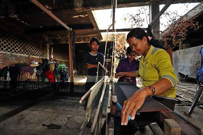 Bewohner in einer ehemaligen Textilfabrik. Die Seidenweberin Can Pheit bei der Arbeit. Bewohner in einer ehemaligen Textilfabrik. Die Seidenweberin Can Pheit bei der Arbeit.