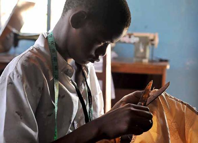 Ein ehemaliges Straßenkind während der Arbeit in der Schneiderwerkstatt Kinder üben traditionelle Tänze.