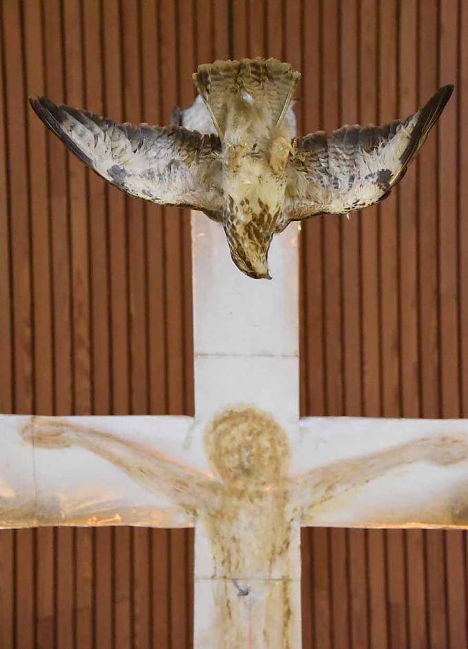 Greifvögel umkreisen ein Kreuz.