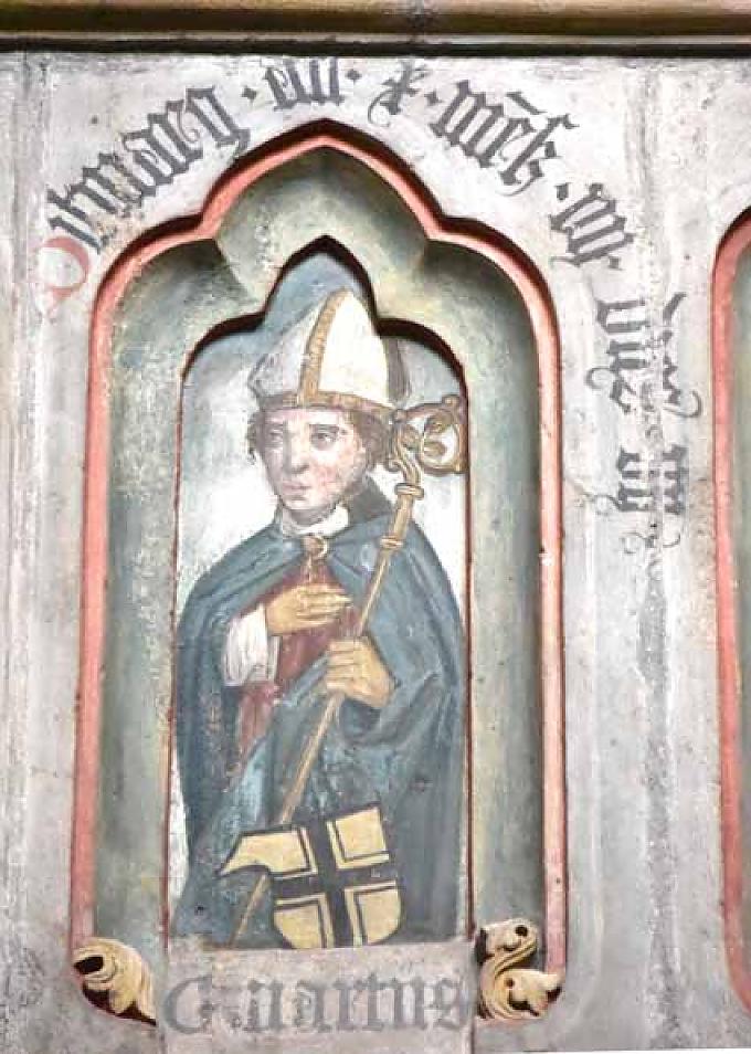 Innmitten des Thietmarbrunnens stützt er sich sinnierend mit den Ellenbogen auf ein Schreibpult und schaut dabei auf den Dom.