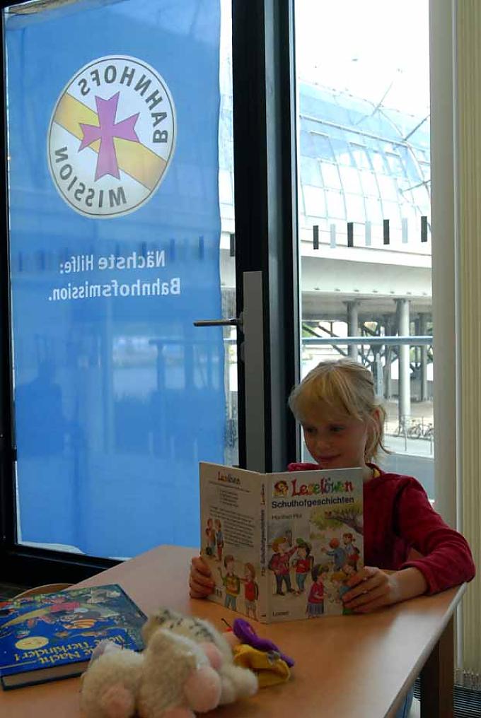 Ein Kind überbrückt die Wartezeit in der Leseecke der Bahnhofsmission