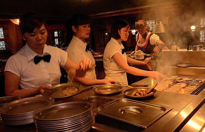 Frau Nga, Frau Mai und Frau Tran (v.li) grillen Rostbratwürste Christkindelsmarkt 1948 - auch Würste sind wieder zu haben.