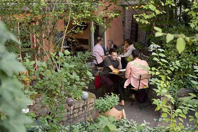 Besucher im Cafe Botanico. Garten zwischen Mietshäusern.