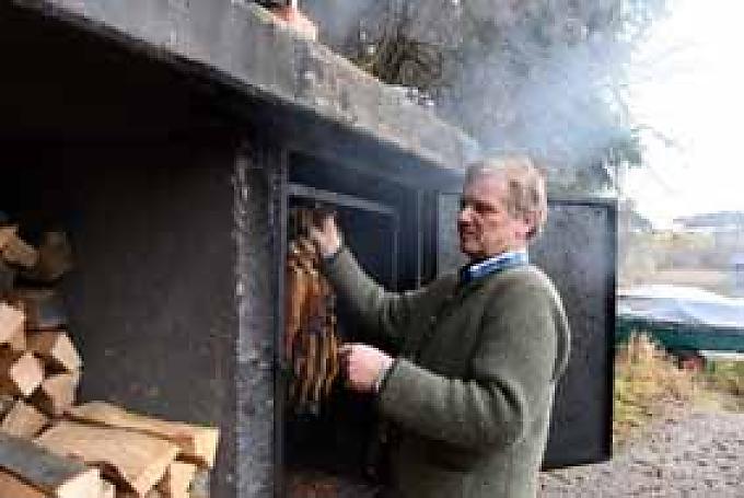 Gerhard Langmaier nimmt frisch geräucherte Fische aus dem Räucherofen direkt am See. Gerhard Langmaier nimmt frisch geräucherte Fische aus dem Räucherofen direkt am See.