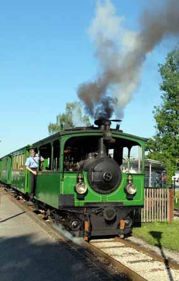 Kaum auf dem Sattel, müssen die Radler auf ihrer Tour auch schon den ersten Halt einlegen. Denn quietschend und große Qualmwolken gen Himmel hinauf ausstoßend, stampft eine historische Dampflok im bayerischen Prien quer über die Fahrbahn. Kaum auf dem Sattel, müssen die Radler auf ihrer Tour auch schon den ersten Halt einlegen. Denn quietschend und große Qualmwolken gen Himmel hinauf ausstoßend, stampft eine historische Dampflok im bayerischen Prien quer über die Fahrbahn.