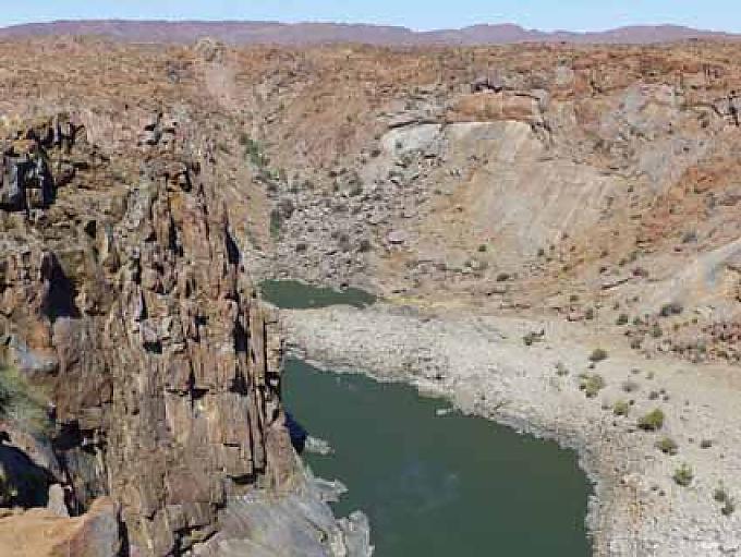 Bizarre Felslandschaft am Oranje River Konzentrierter San-Künstler bei der Arbeit