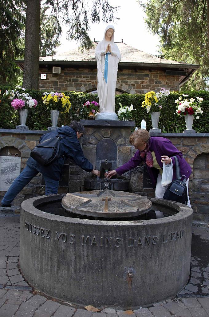 „Taucht die Hände in das Wasser“ steht auf der Brunneneinfassung der Quelle in Banneux