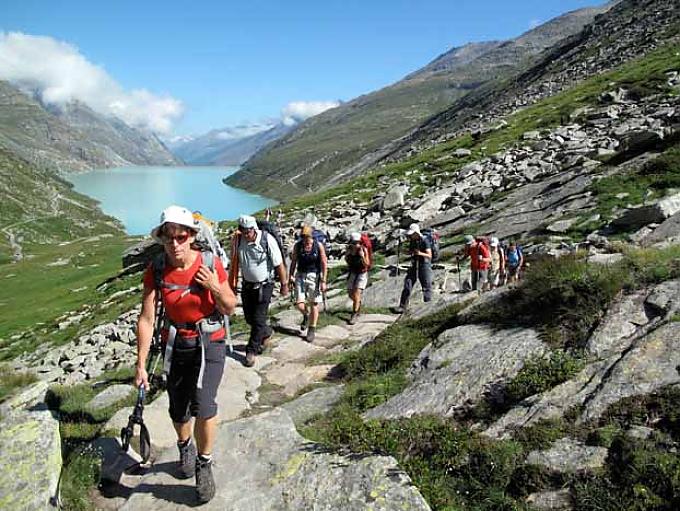 Pilger am Mattmark Stausee. Erschöpfte Pilger rasten und beten in der Rundkirche Saas Balen.